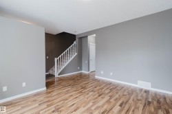 Spacious room featuring wood-finish flooring, light grey walls, and white baseboards - 