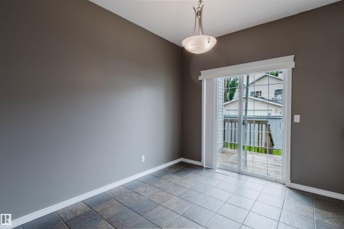 Spacious room featuring floor-to-ceiling sliding glass doors, tile flooring, a contemporary pendant light fixture, and white baseboards - 38 1780 Glastonbury Boulevard, Edmonton, AB 