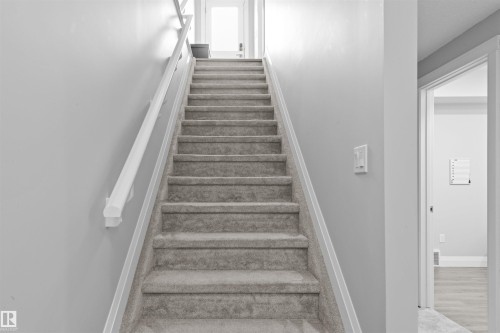 Carpeted staircase featuring a painted wood handrail and light gray wall tones - 389 Charlesworth Drive, Edmonton, AB 