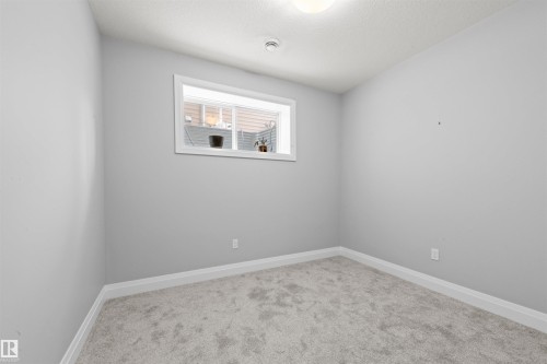 Room featuring light gray carpet flooring, white baseboards, a single light fixture, and a white-framed window - 389 Charlesworth Drive, Edmonton, AB 