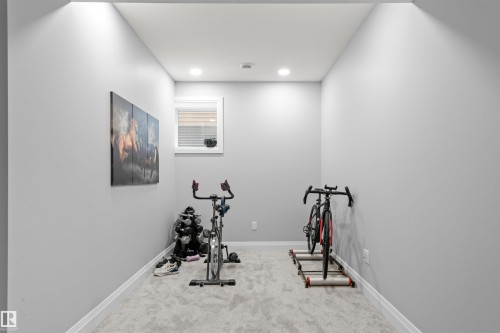 Recessed ceiling lighting illuminates a carpeted room featuring light gray walls, white trim, and a window with blinds - 389 Charlesworth Drive, Edmonton, AB 