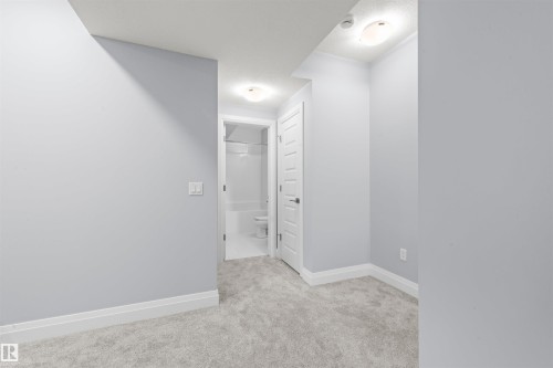 Light gray wall finishes with white baseboards and gray carpet flooring - 389 Charlesworth Drive, Edmonton, AB 