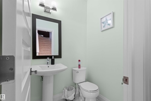 Pedestal sink with chrome faucet, framed mirror, and contemporary vanity lighting fixture - 389 Charlesworth Drive, Edmonton, AB 