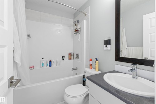Full bathroom featuring a shower-tub combination with white wall surround, a white toilet, and a vanity with a white countertop basin and chrome faucet - 389 Charlesworth Drive, Edmonton, AB 