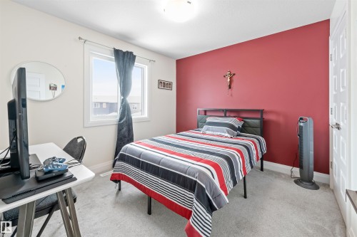 Carpeted room with a single pane window, white trim, and a red accent wall - 389 Charlesworth Drive, Edmonton, AB 