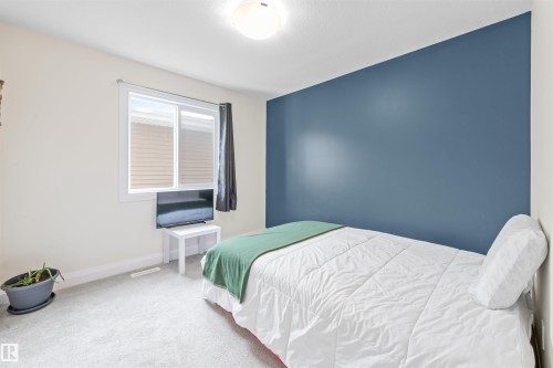 Bedroom featuring a vibrant accent wall, neutral carpeting, and a window with blinds - 389 Charlesworth Drive, Edmonton, AB 