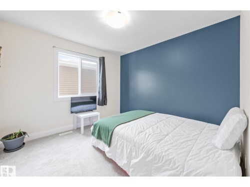 Bedroom featuring a single window with blinds, light-toned carpeting, a recessed ceiling light, and a contrasting accent wall - 389 Charlesworth Drive, Edmonton, AB 
