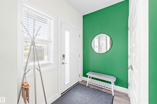 Entryway featuring a white door with smart lock hardware, a rectangular window with blinds, and wood-finish flooring - 389 Charlesworth Drive, Edmonton, AB 