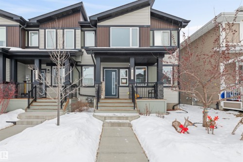 Modern townhome facade featuring multi-tone siding, dark trim, and a prominent front entry with a full-light door - 389 Charlesworth Drive, Edmonton, AB 