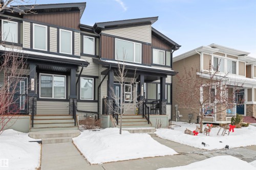 Contemporary two-story townhouse featuring a multi-textured facade with vertical wood-look siding, horizontal vinyl siding, and stone accents - 389 Charlesworth Drive, Edmonton, AB 