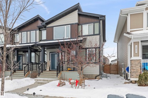 Contemporary townhome exterior featuring multi-toned siding, a covered front porch, a dark entry door, and large windows - 389 Charlesworth Drive, Edmonton, AB 