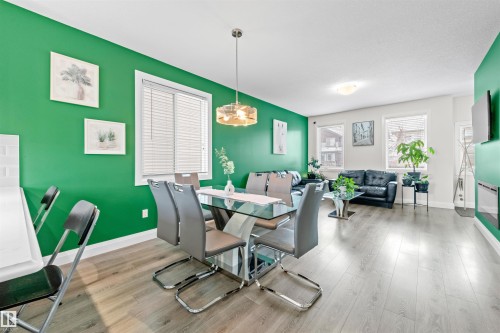 Open-concept living area featuring light wood-finish flooring, white baseboards, and multiple windows with horizontal blinds - 389 Charlesworth Drive, Edmonton, AB 