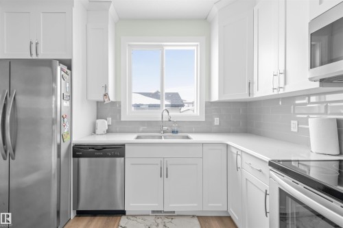 Kitchen featuring white shaker cabinetry, light countertops, and a gray subway tile backsplash - 389 Charlesworth Drive, Edmonton, AB 