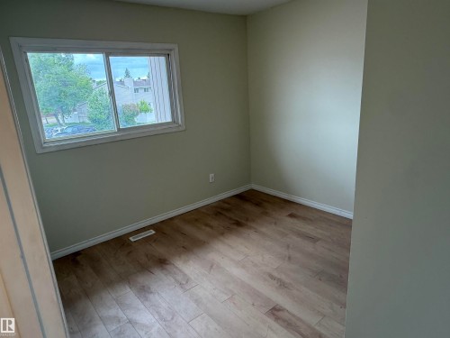 Room featuring wood-finish flooring, light-colored walls, white baseboards, and a white-trimmed window - 14537 121 Street, Edmonton, AB 