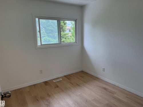 Room featuring wood-finish flooring, white baseboards, and a window with white trim - 14537 121 Street, Edmonton, AB 