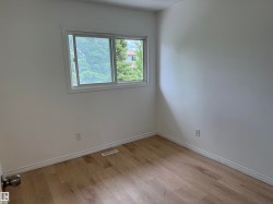Room featuring wood-finish flooring, white baseboards, and a window with white trim - 