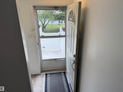 Entryway with wood-finish flooring, white walls, and a multi-pane door with an arched top window - 