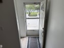 Entryway featuring wood-finish flooring, a white paneled door with a decorative arched window, and a storm door - 14537 121 Street, Edmonton, AB 