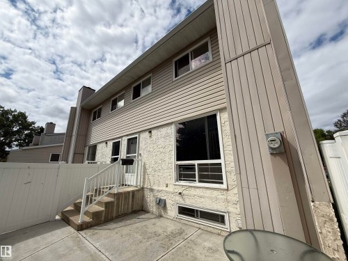 Exterior featuring horizontal siding, textured stucco accents, a concrete patio, and a white privacy fence - 14537 121 Street, Edmonton, AB 