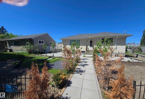 Exterior featuring a textured facade, a gray shingle roof, front steps, and a concrete pathway leading to the entrance - 12432 96 Street, Edmonton, AB 
