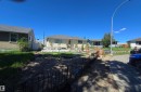 Single-family home featuring a light-colored exterior, an asphalt shingle roof, and a gravel front yard with some planted trees and shrubs - 12432 96 Street, Edmonton, AB 