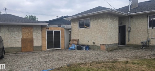 Exterior featuring light-colored stucco-finish siding, a dark shingle roof, and white window frames - 12432 96 Street, Edmonton, AB 