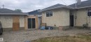Exterior featuring light-colored stucco-finish siding, a dark shingle roof, and white window frames - 12432 96 Street, Edmonton, AB 