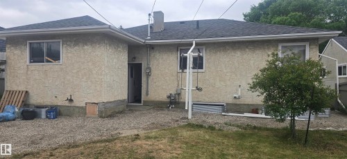 Rear exterior featuring stucco siding, white window trim, and a shingled roof - 12432 96 Street, Edmonton, AB 