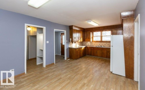 Spacious kitchen featuring warm wood cabinetry, light-toned countertops, and a white refrigerator - 9836 100 Street, Westlock, AB 