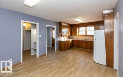 Spacious kitchen featuring warm wood cabinetry, light-toned countertops, and a white refrigerator - 