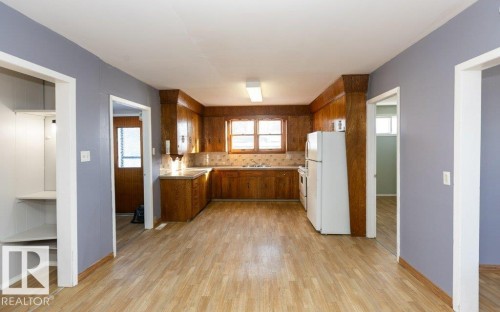 Kitchen featuring wood-finish flooring, wood cabinetry, laminate countertops, and a tiled backsplash - 9836 100 Street, Westlock, AB 