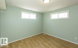 Room featuring two windows with white trim, light green walls, wood-finish flooring, and a flush mount ceiling light fixture - 