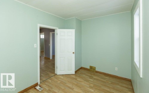 Interior room with light green walls and wood-finish flooring - 9836 100 Street, Westlock, AB 