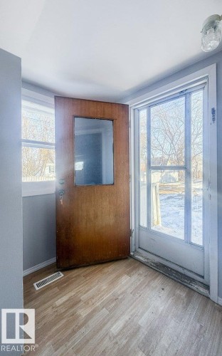 Entryway featuring light wood-finish flooring and a wood front door with a small window pane - 9836 100 Street, Westlock, AB 