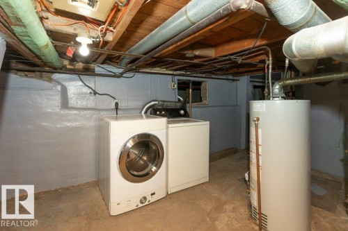 Dedicated laundry area featuring a front-load washer, a dryer unit, and a water heater - 9836 100 Street, Westlock, AB 