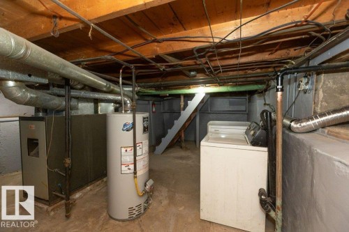 Utility space featuring exposed ceiling joists, a water heater, a furnace system, and foundational walls - 9836 100 Street, Westlock, AB 