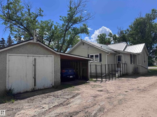 Single-story residence featuring a metal roof, stucco exterior, and black window shutters - 9836 100 Street, Westlock, AB 