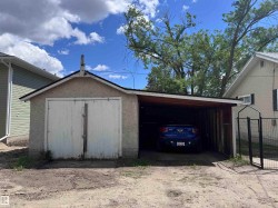 Detached single-car garage featuring a stucco exterior and a side carport with a wood-finish ceiling - 