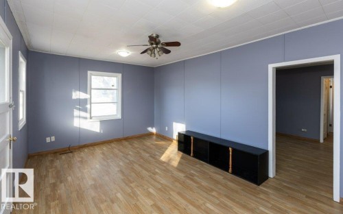 Room with wood-finish flooring, two windows, and a ceiling fan with integrated lighting - 9836 100 Street, Westlock, AB 