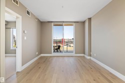 Spacious room featuring wood-finish flooring, light-toned walls, and a sliding glass door leading to a private balcony - 
