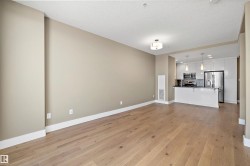 Open-concept living area with wood-finish flooring, a contemporary ceiling light fixture, and neutral wall tones - 