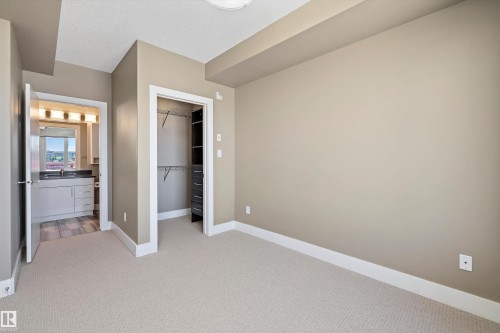 Neutral-toned room featuring light-colored carpeting and white baseboards - 307 11080 Ellerslie Rd Sw, Edmonton, AB 