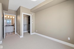 Neutral-toned room featuring light-colored carpeting and white baseboards - 