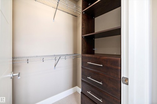Built-in closet system featuring dark wood-finish drawers, open shelving, and chrome wire shelving - 307 11080 Ellerslie Rd Sw, Edmonton, AB 