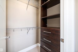 Built-in closet system featuring dark wood-finish drawers, open shelving, and chrome wire shelving - 