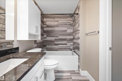 Bathroom featuring a white vanity with a dark stone-finish countertop, undermount sink, and chrome fixtures - 