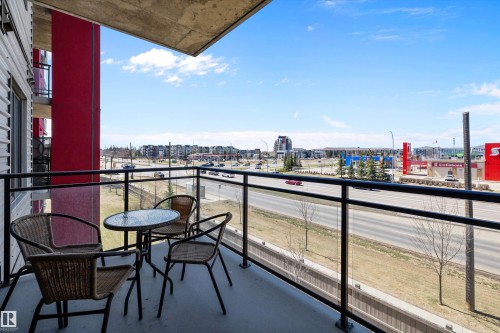 Private west facing balcony featuring concrete flooring and a glass panel railing system with black metal supports. - 307 11080 Ellerslie Rd Sw, Edmonton, AB 