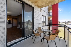 Private west facing balcony featuring concrete flooring and a glass panel railing system with black metal supports. - 