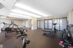Fitness center featuring rubberized flooring, mirrored wall, multiple cardio machines, and strength training equipment. - 