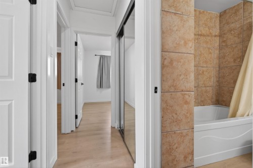 Hallway with light wood-finish flooring, white paneled doors, and matte black hardware - 7304/7306 78 Avenue, Edmonton, AB 